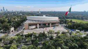 Vista aérea del Auditorio Nacional sobre Paseo de la Reforma, rodeado por el Bosque de Chapultepec, con la bandera monumental y los rascacielos al fondo